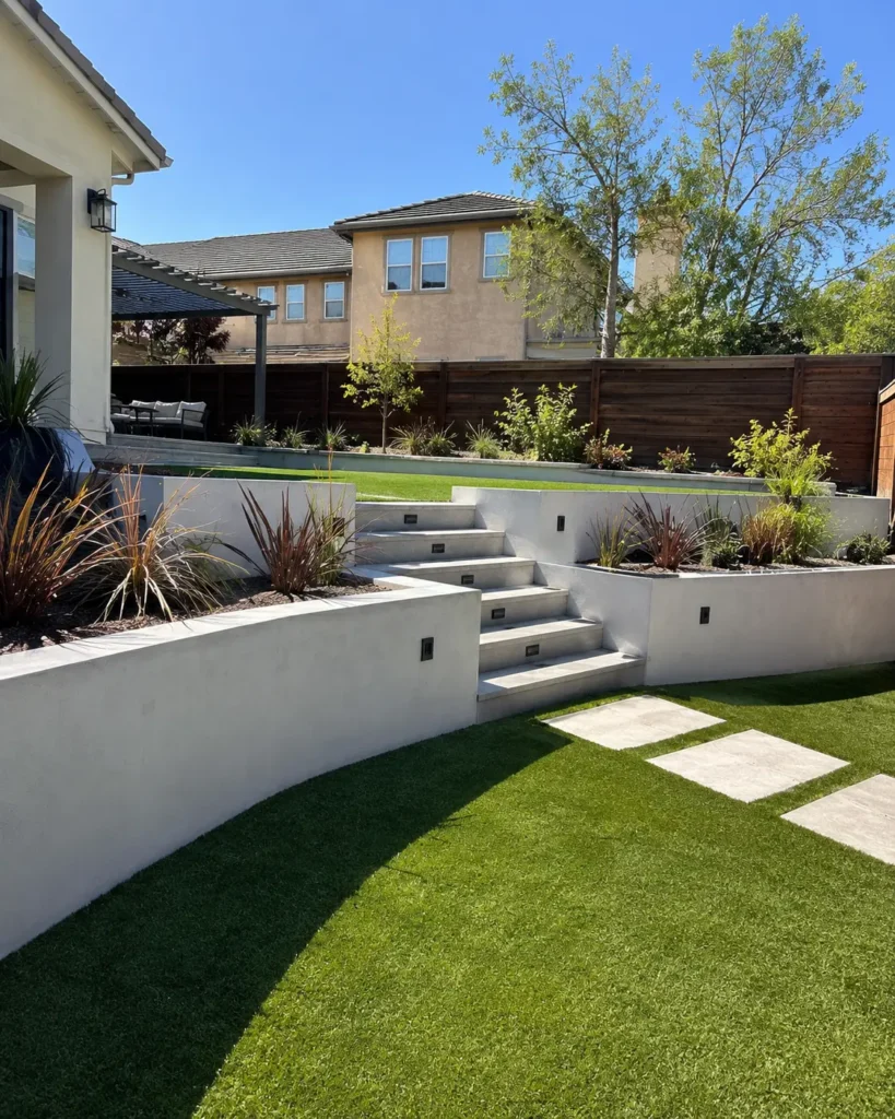 Backyard retaining walls with steps and turf by Be Home Remodeling